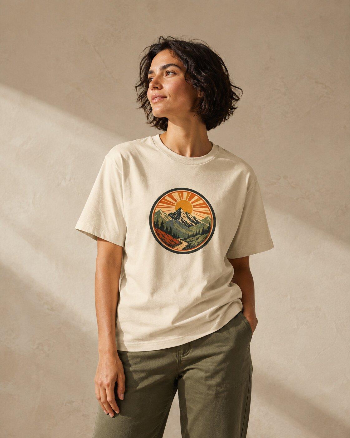 A model wearing a cream mountain-print tee with olive trousers in a sunlit studio